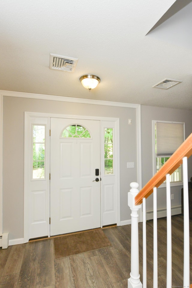 foyer entrance with wood finished floors, baseboards, stairs, baseboard heating, and crown molding