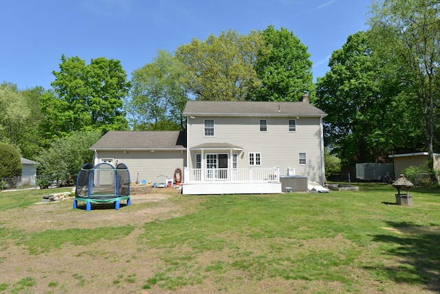 rear view of house featuring a trampoline, a wooden deck, a chimney, and central AC unit