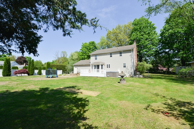 back of house with a chimney, a trampoline, and a wooden deck