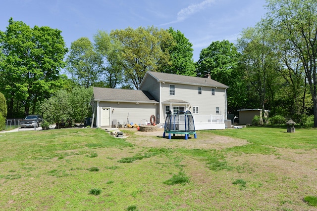 back of property featuring a lawn, a deck, an outdoor fire pit, a chimney, and view of scattered trees