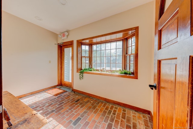 foyer entrance featuring baseboards and brick floors