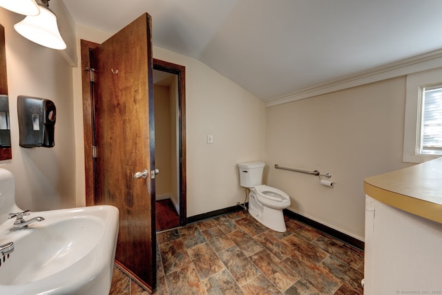 bathroom featuring a sink, stone finish floors, baseboards, toilet, and lofted ceiling