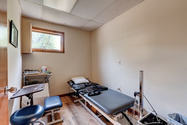 exercise area featuring wood finished floors, a paneled ceiling, and baseboards