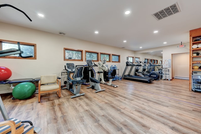 exercise room with wood finished floors, recessed lighting, and a baseboard heating unit