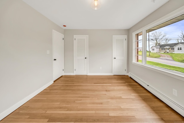 636 Thompson Rd, Thompson, CT 06277 - unfurnished bedroom with a baseboard radiator, multiple closets, baseboards, and light wood-type flooring