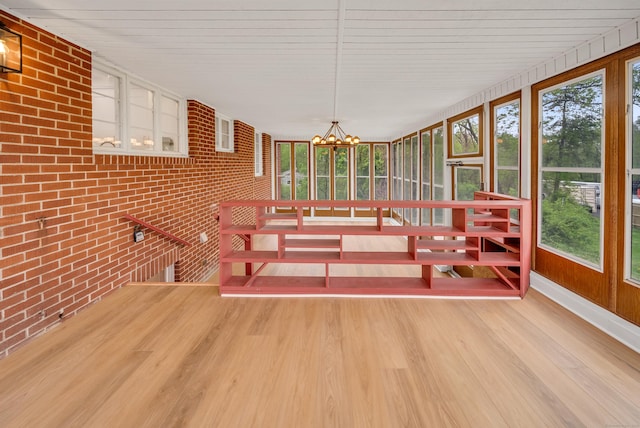 636 Thompson Rd, Thompson, CT 06277 - unfurnished dining area featuring brick wall, wood finished floors, and a chandelier