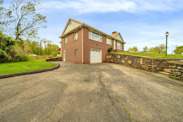 636 Thompson Rd, Thompson, CT 06277 - view of side of home featuring brick siding, driveway, an attached garage, and a chimney