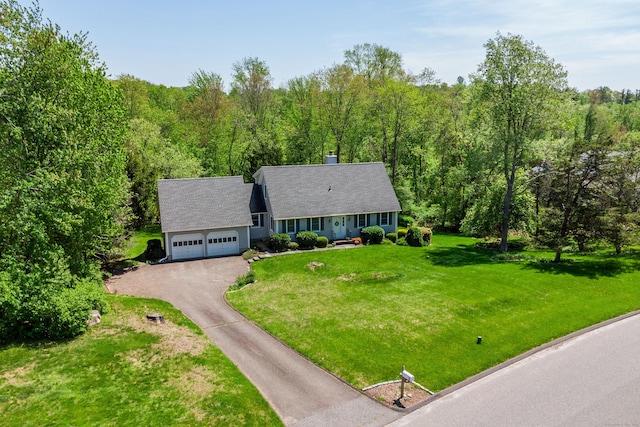 view of front facade featuring asphalt driveway, an attached garage, a front yard, and a view of trees