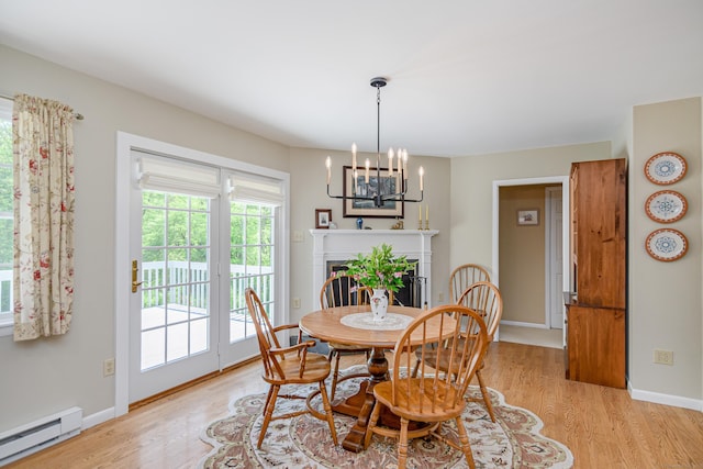dining room featuring a baseboard heating unit, light wood-style floors, a chandelier, and baseboards
