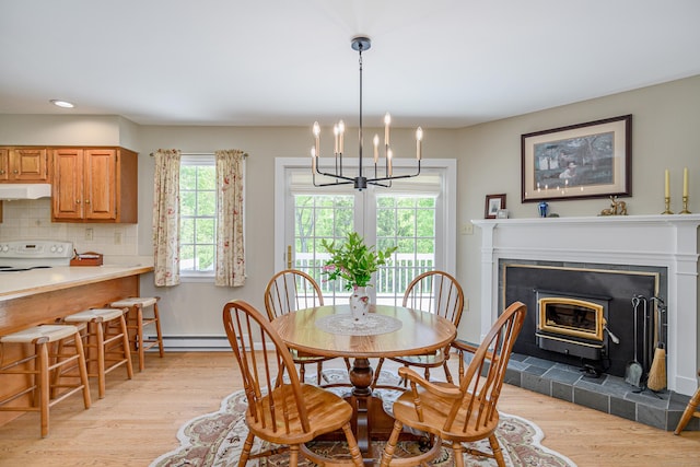 dining area with light wood-style flooring, a chandelier, recessed lighting, a tile fireplace, and baseboard heating