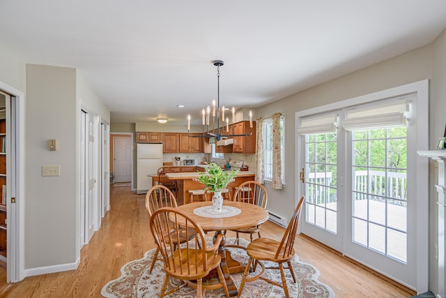 dining space with baseboard heating, light wood finished floors, a chandelier, and baseboards
