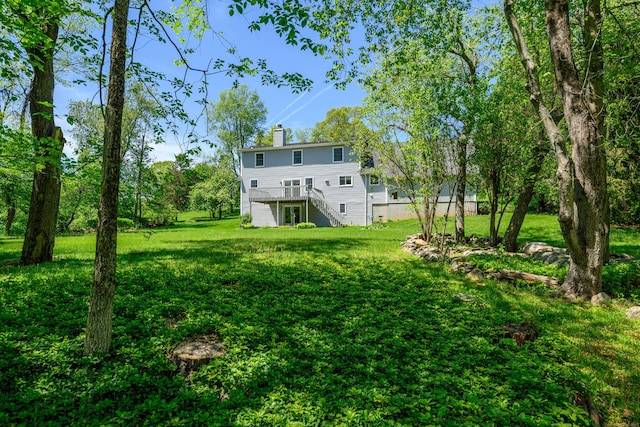 view of green lawn with stairway and a deck