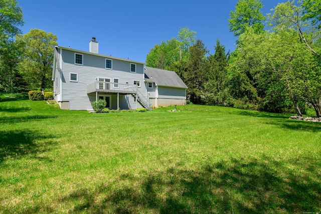 rear view of property with stairway, a deck, a chimney, and a lawn