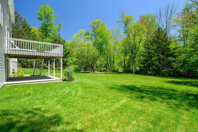 view of grassy yard featuring a deck and stairs