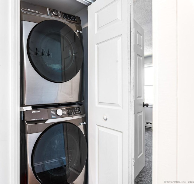 17 Emily Rd, East Windsor, CT 06016 - laundry room featuring stacked washer / dryer, a baseboard radiator, and a textured ceiling