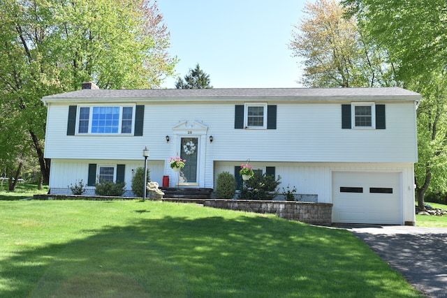 bi-level home with an attached garage, a chimney, driveway, and a front lawn