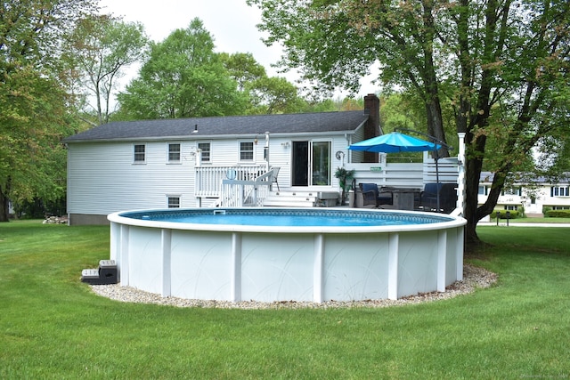 back of house with a chimney, a lawn, a wooden deck, and an outdoor pool