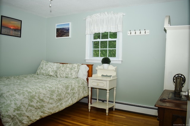 bedroom with baseboard heating and wood finished floors