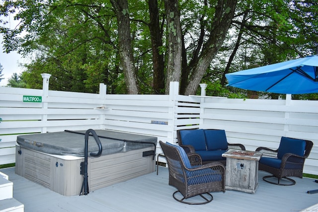 deck featuring a hot tub, fence, and an outdoor living space with a fire pit