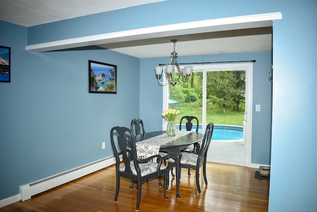 dining space featuring baseboard heating, a chandelier, wood finished floors, and baseboards