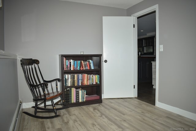 sitting room with baseboard heating, wood finished floors, and baseboards