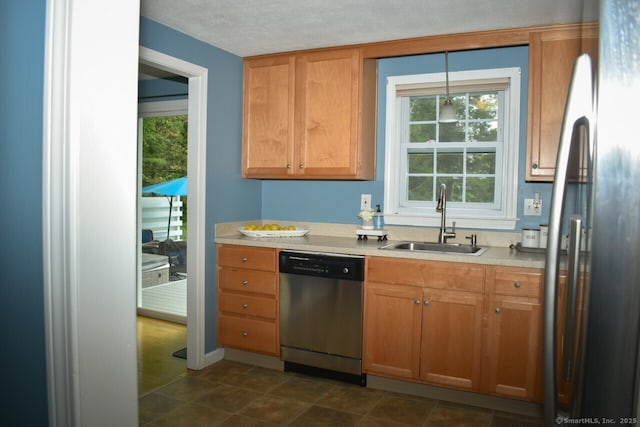 kitchen featuring stainless steel dishwasher, a sink, refrigerator, light countertops, and plenty of natural light