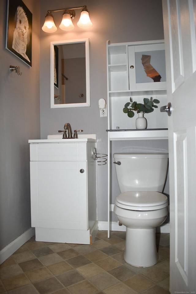 bathroom featuring baseboards, toilet, and vanity