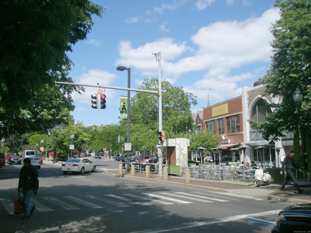 view of asphalt road featuring street lights, traffic lights, sidewalks, and curbs