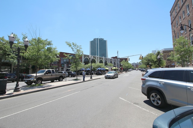 view of asphalt street with street lights, curbs, and sidewalks