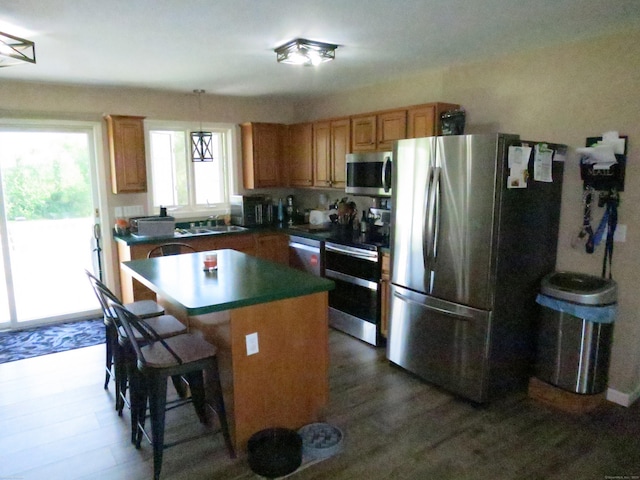 23 Hell Hollow Rd, Sterling, CT 06384 - kitchen featuring appliances with stainless steel finishes, a kitchen island, a breakfast bar, brown cabinets, and hanging light fixtures