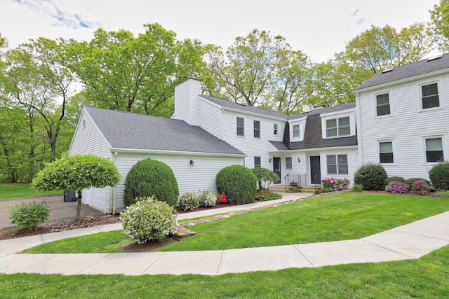 view of front facade featuring a shingled roof, a front lawn, and an attached garage