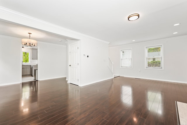 unfurnished living room featuring wood finished floors, baseboards, stairs, a chandelier, and crown molding