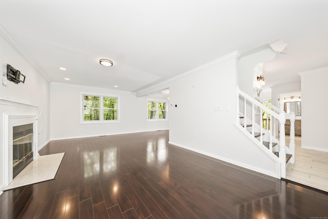 unfurnished living room featuring a fireplace, crown molding, baseboards, stairway, and wood finished floors