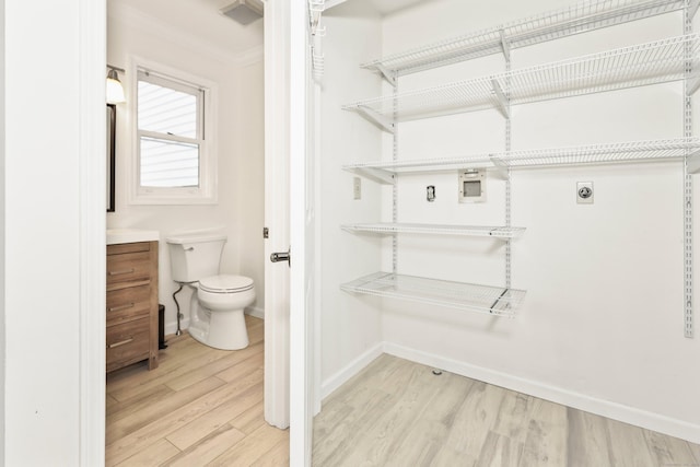 bathroom featuring wood finished floors, baseboards, toilet, crown molding, and vanity