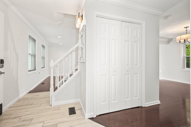 stairway with wood finished floors, crown molding, recessed lighting, baseboards, and a chandelier