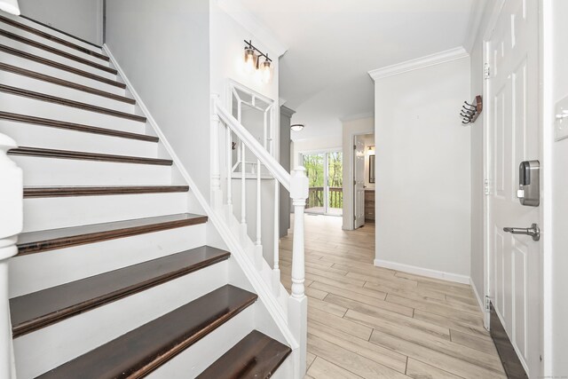 stairs featuring wood finished floors, ornamental molding, and baseboards