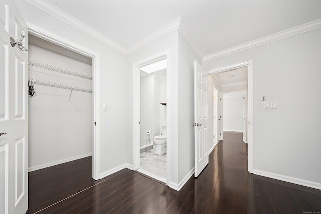 hallway featuring dark wood-style flooring, ornamental molding, and baseboards