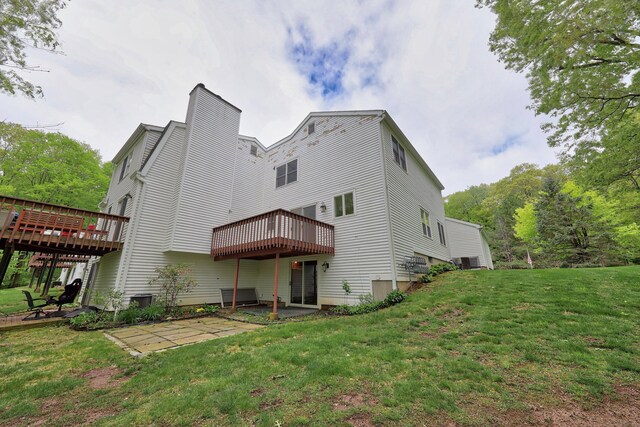 back of house featuring a patio, a deck, a lawn, and central AC unit