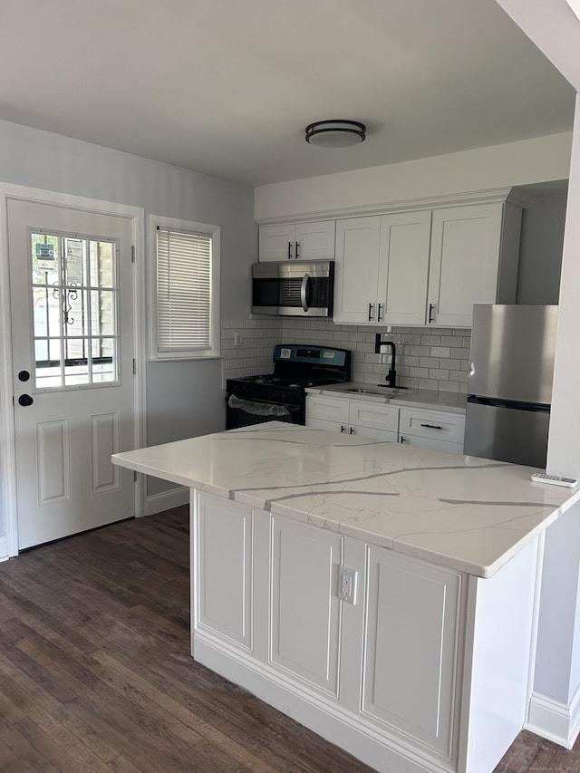 kitchen with appliances with stainless steel finishes, white cabinets, backsplash, dark wood-style floors, and light stone counters