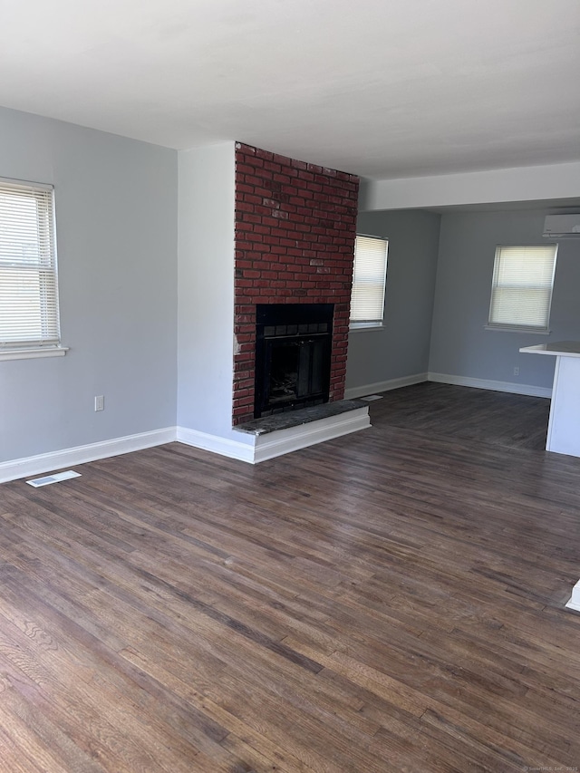 unfurnished living room featuring plenty of natural light, dark wood-style floors, and baseboards