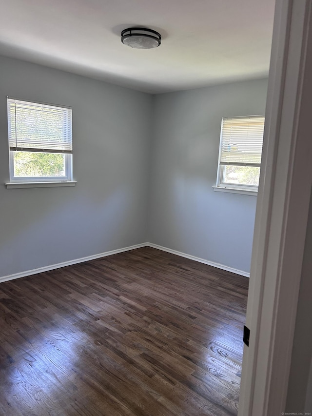 spare room with dark wood finished floors and baseboards