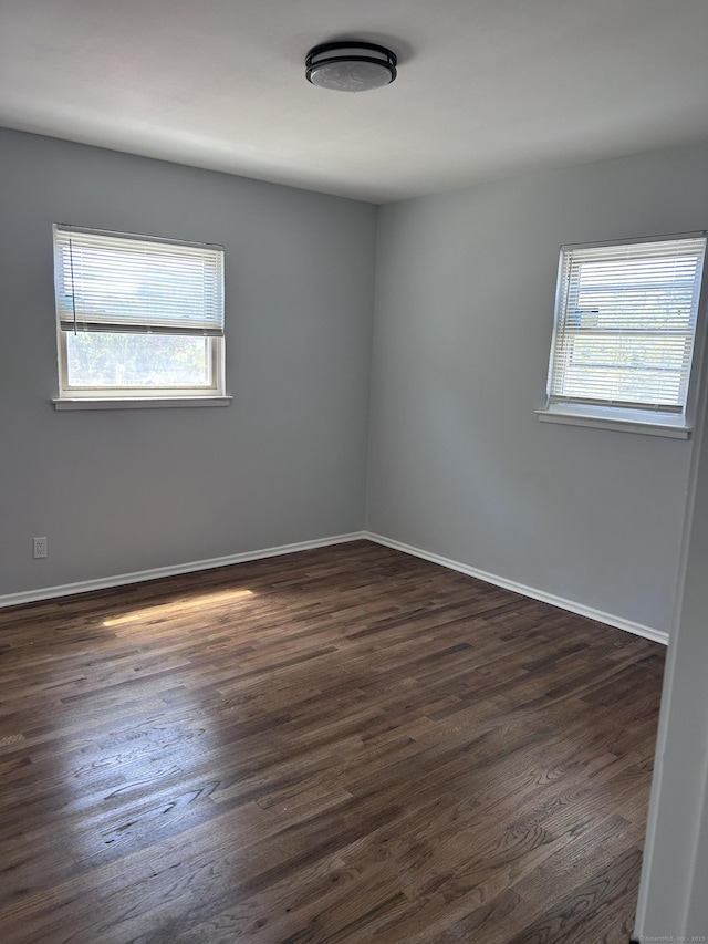unfurnished room with dark wood-type flooring and baseboards