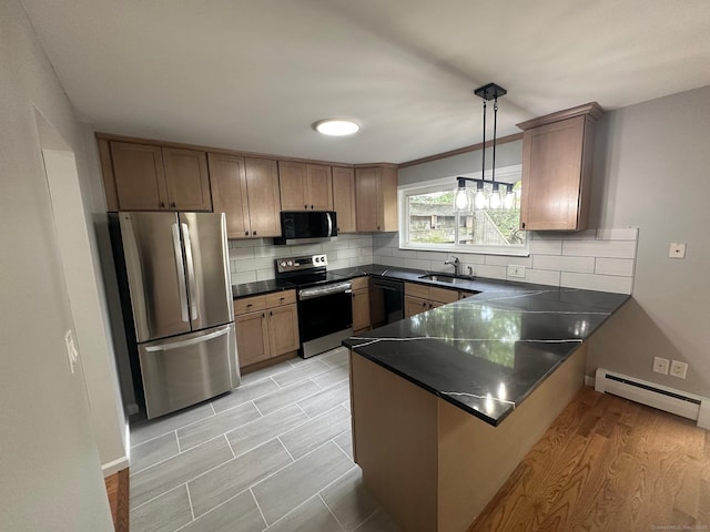 kitchen featuring black appliances, a peninsula, baseboard heating, dark countertops, and tasteful backsplash