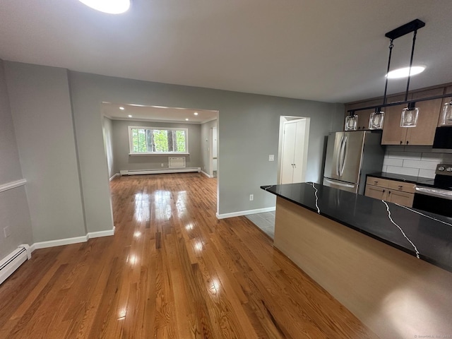 kitchen with appliances with stainless steel finishes, dark countertops, a baseboard heating unit, wood finished floors, and baseboards