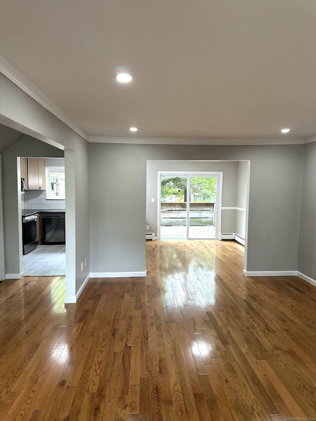 spare room featuring crown molding, a baseboard radiator, hardwood / wood-style floors, recessed lighting, and baseboards