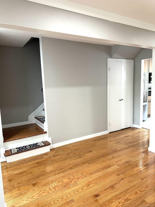 basement with stairway, baseboards, wood finished floors, and freestanding refrigerator