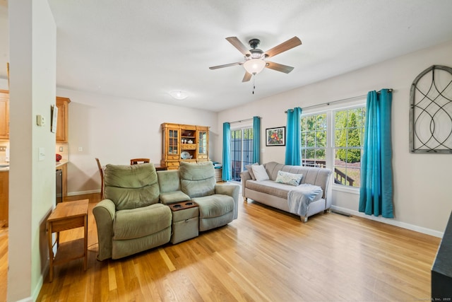 living room with a ceiling fan, light wood-type flooring, and baseboards