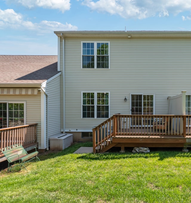 rear view of house featuring a wooden deck and a lawn