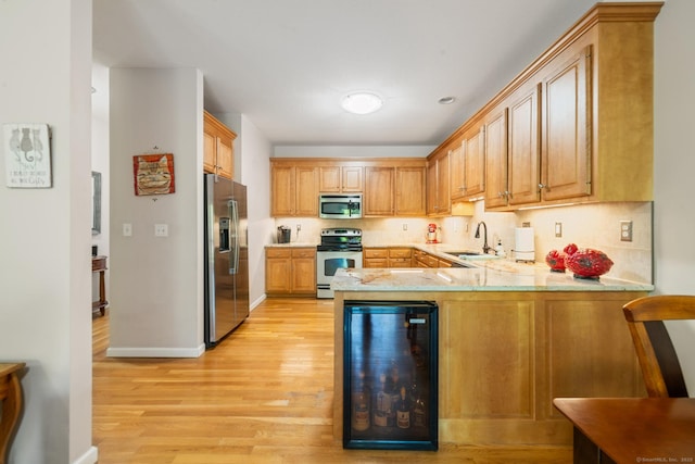 kitchen featuring appliances with stainless steel finishes, wine cooler, a sink, and light wood finished floors