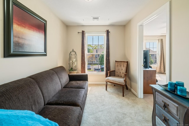 sitting room featuring healthy amount of natural light, light colored carpet, and baseboards